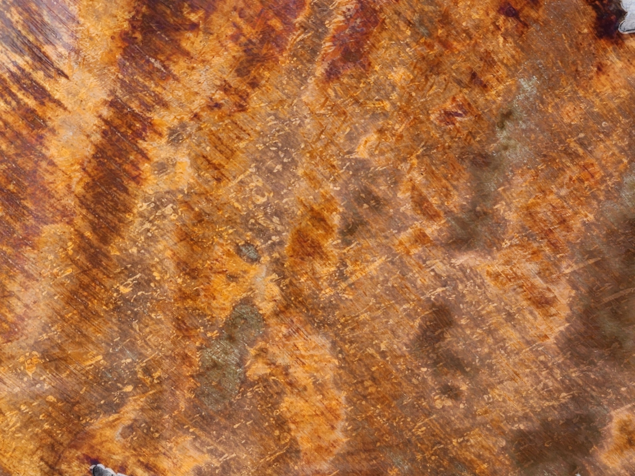 Close-up of steel metal surface with copper patina that is brown and orange hues